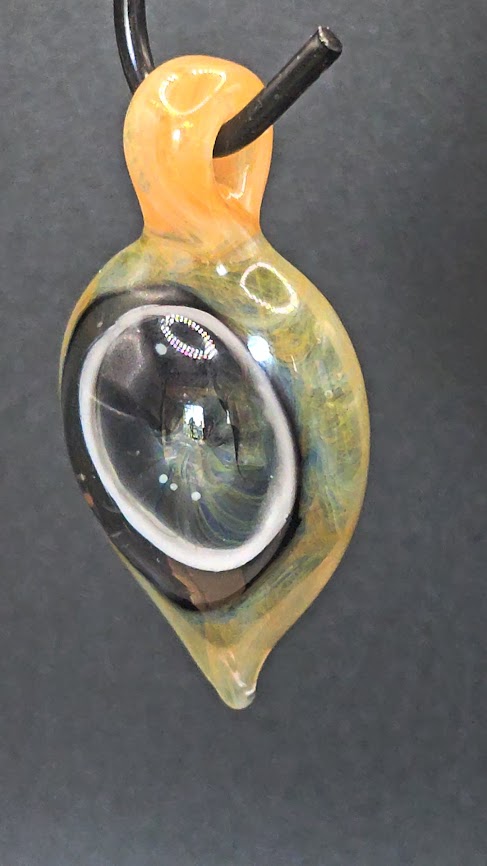 Glass pendant with a clear center and yellow and green edges on a dark background